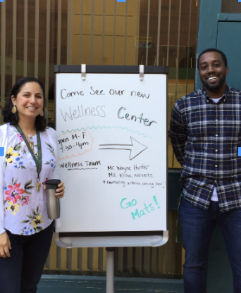 Wayne Hunter and Elisa Nevarez pose next to the Wellness Center board outside. 