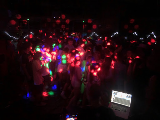 Students dance in the dark with colorful lights. 