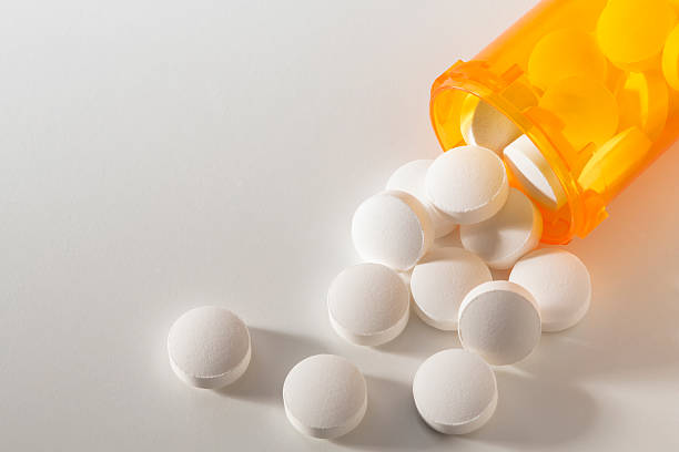 Prescription medication spilling from an open bottle onto a white surface.